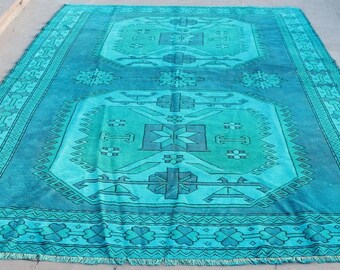 May include: A teal blue rug with a geometric pattern. The rug has a fringed edge and a faded, vintage look.