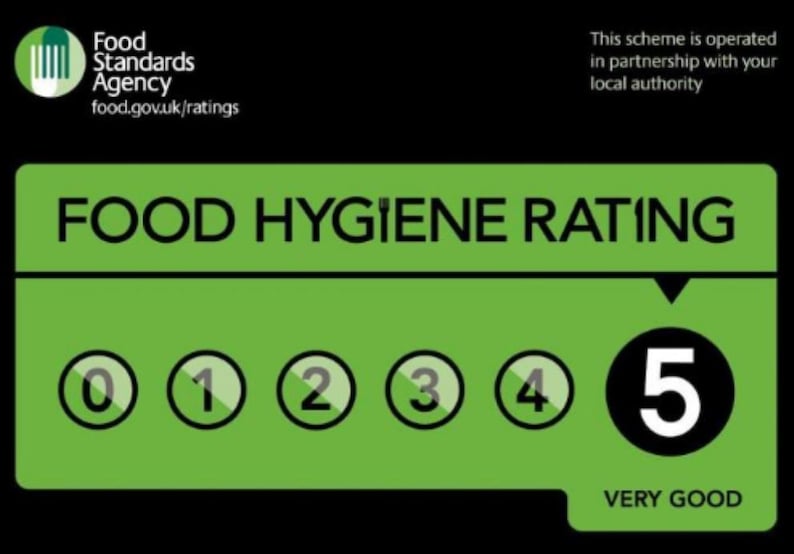 May include: A green and black Food Standards Agency sign displaying a Food Hygiene Rating of 5. The graphic features the text Food Hygiene Rating, a row of numbers from 0 to 5 with the number 5 highlighted in a black circle, and the text Very Good.