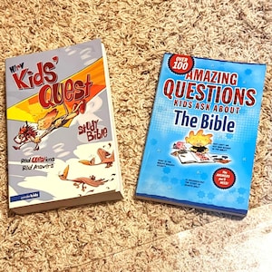 Puede incluir: Se muestran dos libros infantiles. Uno se titula "Kids' Quest Study Bible" con una ilustración de dibujos animados. El otro es "Amazing Questions Kids Ask About The Bible" con una portada azul y gráficos de dibujos animados.