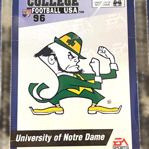 May include: A College Football USA '96 trading card featuring the University of Notre Dame mascot in green and gold. The card has the EA Sports logo and the text "University of Notre Dame".