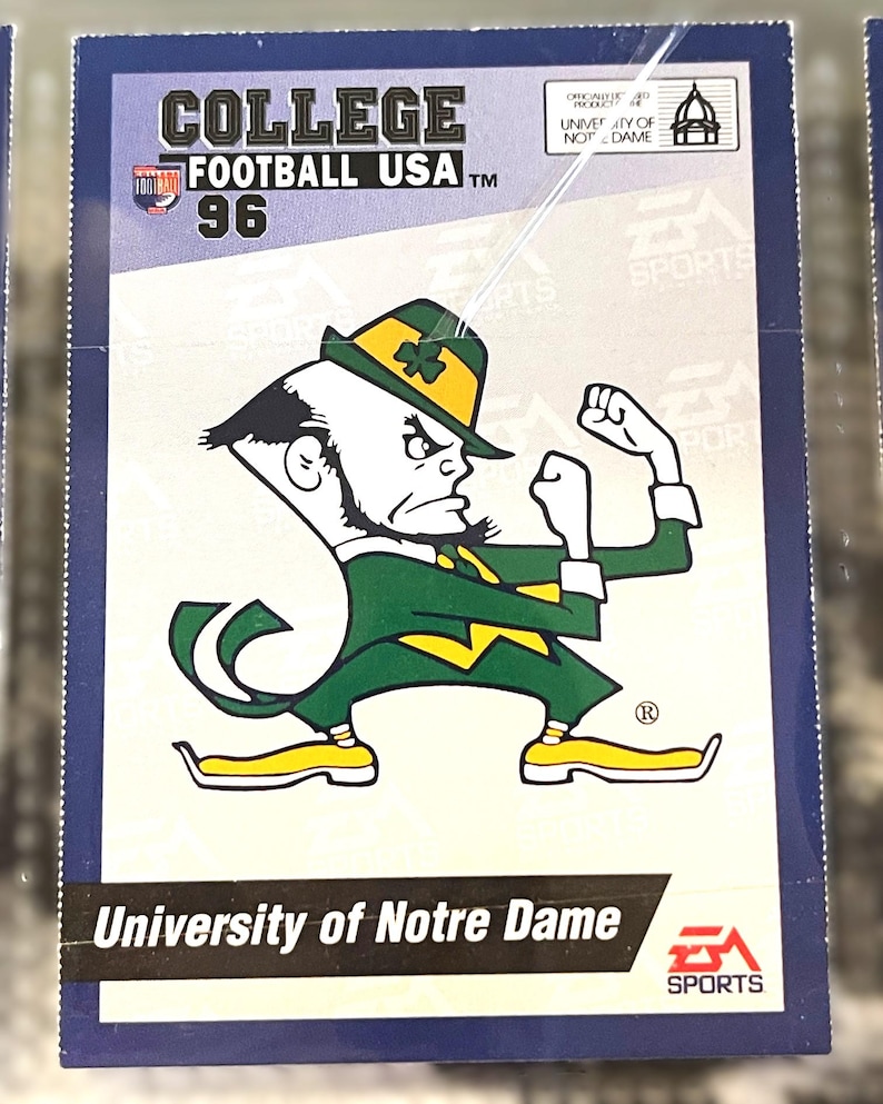 May include: A College Football USA '96 trading card featuring the University of Notre Dame mascot in green and gold. The card has the EA Sports logo and the text "University of Notre Dame".
