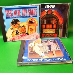 May include: Three CD cases with vintage album art. The top left case reads "THESE WERE OUR SONGS" with a couple embracing. The top right case reads "1949" with a jukebox illustration. The bottom case reads "SONGS OF WORLD WAR II" with a dancing couple.
