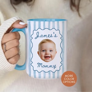 Op de afbeelding: Een grote witte mok met een lichtblauwe binnenkant en handvat. De mok heeft een foto van een baby met de tekst "James's Mommy" in een decoratief kader. De mok heeft verticale lichtblauwe strepen.