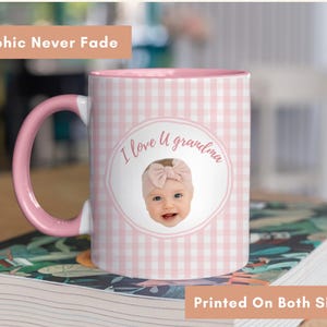 Op de afbeelding: Een roze en witte geruite mok met een roze handvat en binnenkant. De mok heeft een foto van een baby met een roze strik en de tekst "I love U grandma". De mok heeft de tekst "Graphic Never Fade" en "Printed On Both Sides".