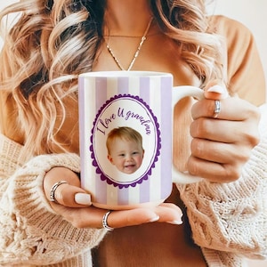 Op de afbeelding: Witte keramische mok met een paars en wit gestreept ontwerp. De mok heeft een paarse ovaal met de tekst "I love U grandma" en een foto van een baby. De mok heeft een wit handvat.