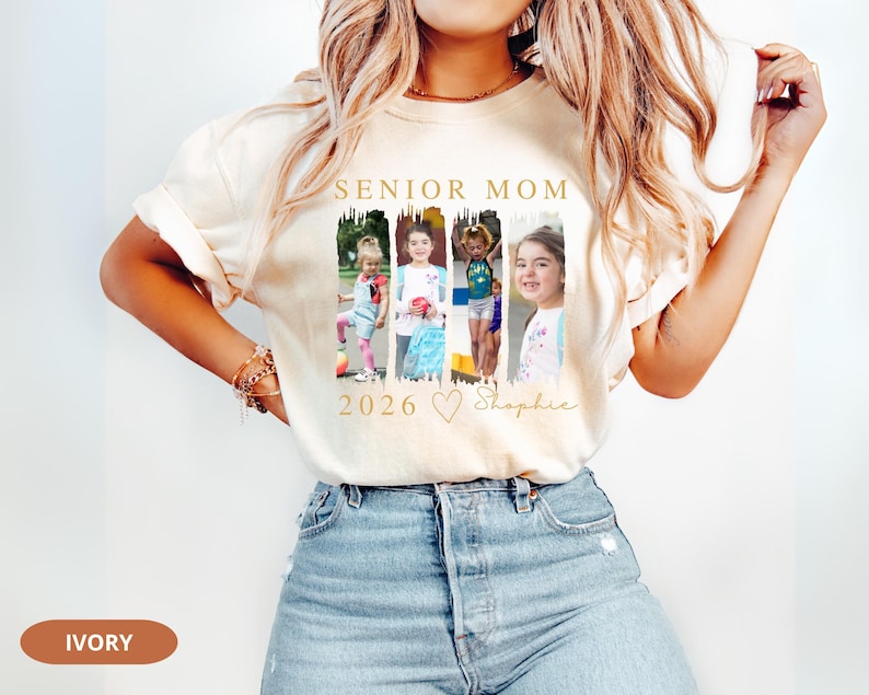 May include: Ivory-colored t-shirt with the text "SENIOR MOM 2026" in gold. The shirt features four framed photos of children. The name "Shaphie" is written in script below the photos. The shirt is made of soft material.