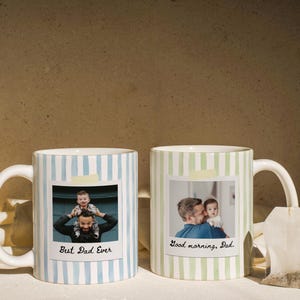 May include: Two white ceramic mugs with striped patterns. One mug has blue stripes and the text "Best Dad Ever" with a photo. The other mug has green stripes and the text "Good morning, Dad" with a photo. A tea bag hangs from the second mug.