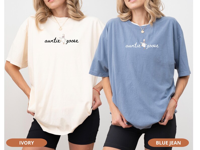 Puede incluir: Dos camisetas holgadas, una marfil y otra azul, con el texto "auntie goose" y un gr&aacute;fico de ganso. Las camisetas se combinan con pantalones cortos negros. La imagen muestra los colores y el dise&ntilde;o de las camisetas.