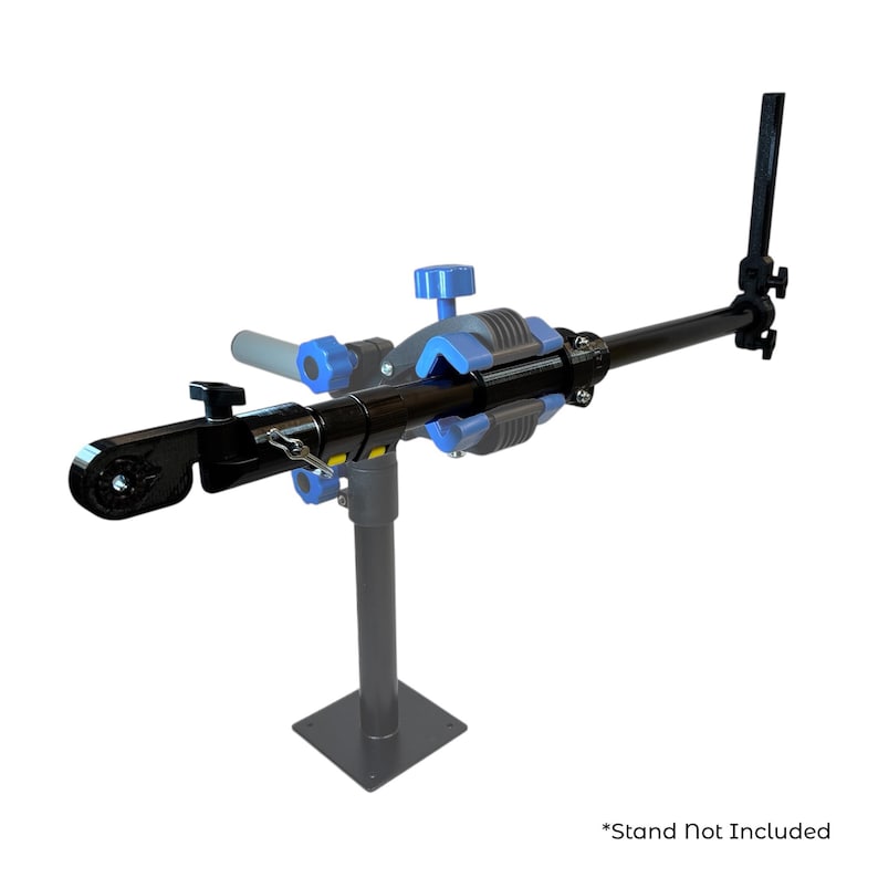 Pode incluir: Um suporte de repara&ccedil;&atilde;o de bicicletas preto e azul com componentes ajust&aacute;veis. O suporte tem uma base quadrada e um bra&ccedil;o longo com uma bra&ccedil;adeira. O texto "*Stand Not Included" &eacute; vis&iacute;vel na parte inferior.