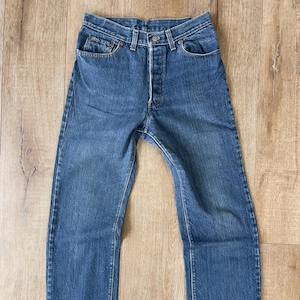 May include: A pair of blue denim jeans with a button fly and five pockets.