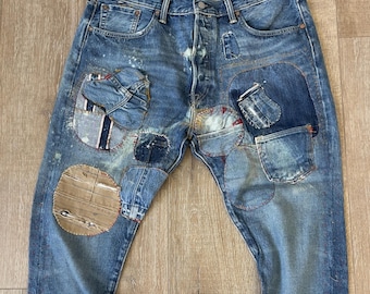 May include: Blue denim jeans with multiple patches and distressed details. The jeans have a relaxed fit and a straight leg.