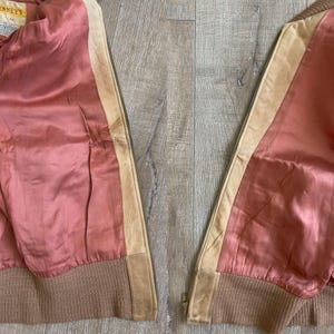 May include: A vintage jacket with a pink satin lining, tan leather accents, and a brown ribbed knit hem. The jacket has a zipper closure and a tag that reads "Kenney's".