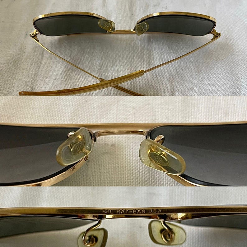 Puede incluir: Gafas de sol doradas con lentes oscuras. Las gafas tienen una forma de aviador cl&aacute;sica con doble puente y almohadillas nasales. El texto "B&L RAY-BAN USA" es visible en la montura.