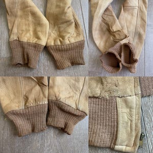 May include: Close-up of vintage tan leather jacket sleeves with brown ribbed knit cuffs. The leather shows signs of wear and age, with visible creases and variations in color. The cuffs are a darker shade of brown.
