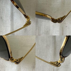 Puede incluir: Primer plano de gafas de sol con montura dorada y lentes oscuras. La imagen destaca los intrincados detalles de las bisagras y las patillas, mostrando la artesan&iacute;a. Las monturas doradas contrastan con las lentes oscuras.
