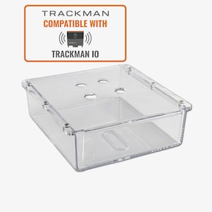May include: A clear, rectangular plastic container with rounded corners and small holes on the top surface. The container has a rectangular cutout on the front. The text "TRACKMAN COMPATIBLE WITH TRACKMAN IO" is displayed in an orange rectangle above the container.
