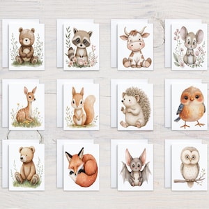May include: A collection of twelve greeting cards featuring watercolor illustrations of woodland animals. Each card showcases a different animal, including a bear, raccoon, cow, mouse, deer, squirrel, hedgehog, owl, fox, and bat, with floral accents.