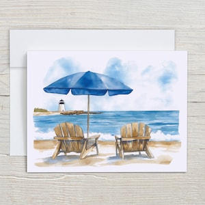 May include: Watercolor art print of a beach scene with two wooden Adirondack chairs under a blue umbrella. The ocean and a lighthouse are in the background. The print is on a white card with a white envelope.