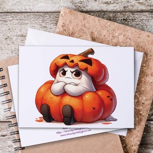 May include: A white greeting card featuring a cartoon pumpkin character with an angry expression. The pumpkin is orange with a brown stem and black shoes. The card is on a wooden surface with a corkboard.