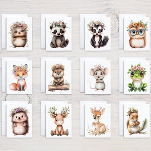May include: A collection of greeting cards featuring watercolor illustrations of woodland animals. Each card showcases a different animal, such as a hedgehog, raccoon, and fox, adorned with floral crowns. The cards are set against a white background.