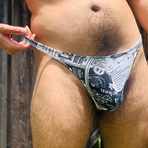 May include: Black and white patterned underwear with a newspaper print design. The print includes the words "Facial Tissue", "Ivory Liquid", "Chicken", and "$1".