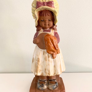 Vintage keramieken beeldje van een meisje met motorkap uit de jaren 70 doet de afwas terracotta bruin