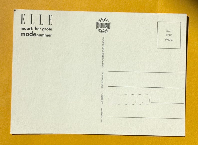 May include: A cream-colored postcard with the word "ELLE" at the top, followed by text in Dutch. The postcard has a "Boomerang Cards" logo and the words "NOT FOR SALE" in a box. Horizontal lines are at the bottom.
