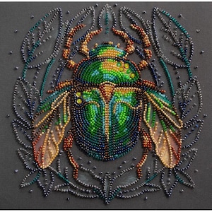 Può includere: Uno scarabeo verde, blu e oro con ali è circondato da un motivo floreale perlato. Lo scarabeo è fatto di perline ed è un'immagine ravvicinata.