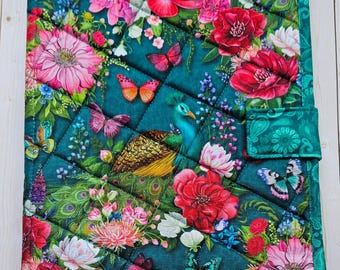 May include: A rectangular quilted fabric cover featuring a dark teal background with a vibrant print of pink and red flowers, green peacock feathers, and colorful butterflies. The cover includes a small side tab closure and diamond stitching.