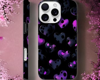 May include: Black phone case with a pattern of purple and black hearts. The hearts have a polka dot design. The case is shown from the front and side, with a pink floral background.