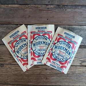 Puede incluir: Tres paquetes de papel de aluminio de tabaco de mascar Union Workman vintage. Cada paquete presenta un diseño circular rojo y azul con el texto "Union Workman Chewing Tobacco" y "New Foil Pack" sobre un fondo crema.