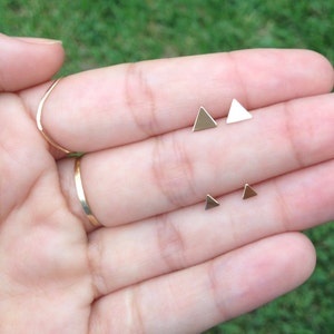 May include: A set of four gold triangle stud earrings. Two of the earrings are larger than the other two.