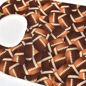 May include: A brown and white bib with a football pattern. The bib has a large opening for the neck and a smaller opening for the head.