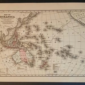 Op de afbeelding: Een antieke kaart van Oceanië, die de eilanden en continenten van de Stille Oceaan toont. De kaart is gedrukt in zwart-wit met bruine en rode accenten. De kaart heeft de titel "Map of Oceania" en bevat de tekst "Engraved to illustrate Mitchell's New Intermediate Geography."