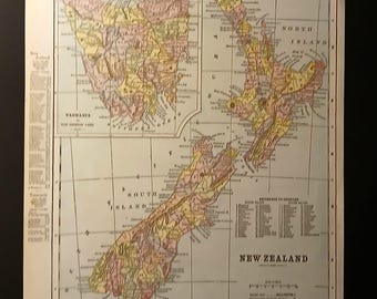 May include: Vintage map of New Zealand, featuring detailed geographical information. The map includes the North and South Islands, Tasmania, and surrounding areas. The map is in shades of beige, yellow, and pink, with text labels and a reference key.