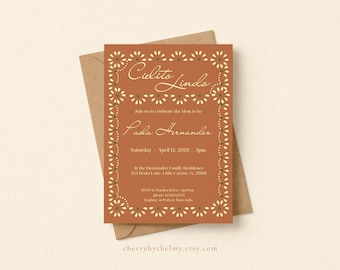 Puede incluir: Una tarjeta de invitación rectangular en color naranja terracota con un borde floral en crema y verde. El texto dice Cielito Lindo, Join us to celebrate the Mom to be, Paola Hernandez, Saturday April 12, 2028, 3pm, y detalles del evento.
