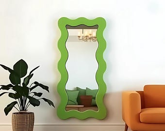 May include: A green wavy-shaped full-length mirror with a reflective surface. The mirror is hanging on a white wall.