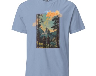 May include: A light blue t-shirt with a graphic print of two figures walking towards a castle in a forest. The sky is a light blue with orange and white clouds.
