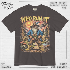May include: Dark gray t-shirt with the text "WHO RUN IT" in yellow. The graphic features a wizard with a long white beard, wearing a blue coat and brown pants, standing in a forest setting. The shirt is labeled "HEAVY WEIGHT GARMENT DYED TEE".