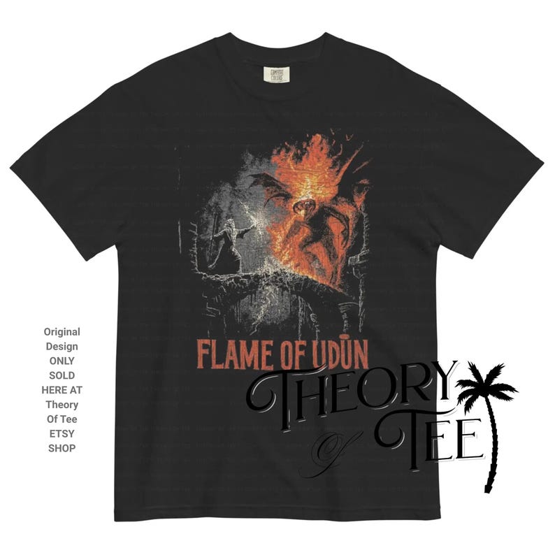 May include: Black t-shirt featuring a graphic design with the text "FLAME OF UDUN". The design includes a fiery image of a creature and a figure. The shirt also has the text "THEORY OF TEE".