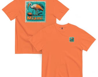 Könnte beinhalten: Orangefarbene T-Shirts mit einem Miami-Design. Auf der Rückseite des Shirts befindet sich eine stempelartige Grafik eines Vogels, eines Fußballs und das Wort "Miami". Die Vorderseite des Shirts hat eine kleinere Version des gleichen Designs.