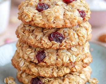 May include: A stack of four oatmeal cookies with cranberries on a light blue plate. The cookies are golden brown and have a slightly crispy texture.