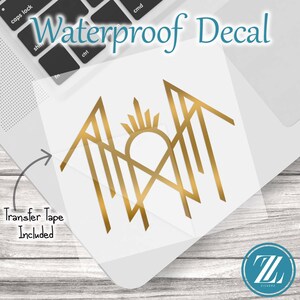 May include: A gold-colored waterproof decal featuring a geometric, stylized sunburst design with sharp, angular lines. The decal is presented on a clear backing sheet with transfer tape included, as indicated by the text on the image.