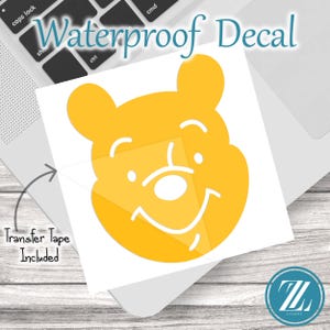 May include: A yellow waterproof decal featuring a smiling bear face. The decal has a white background and includes the text "Waterproof Decal" and "Transfer Tape Included". The decal is on a laptop.