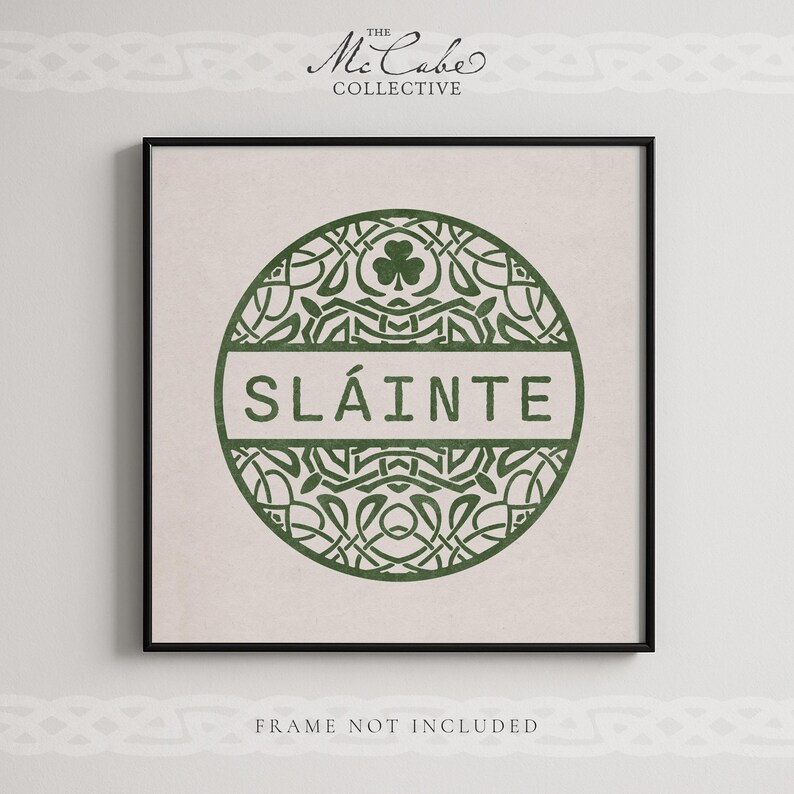 May include: A square wall art print featuring a dark green circular emblem with intricate Celtic knotwork patterns and a shamrock icon. The word SL&Aacute;INTE is printed in a horizontal band across the center. The text THE MCCABE COLLECTIVE appears above and FRAME NOT INCLUDED below.