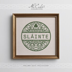 May include: A square wall art print in a gold frame featuring a green circular design with intricate knotwork, a shamrock icon, and the text SL&Aacute;INTE in the center. Above the frame is the text THE MCCABE COLLECTIVE and below is FRAME NOT INCLUDED.