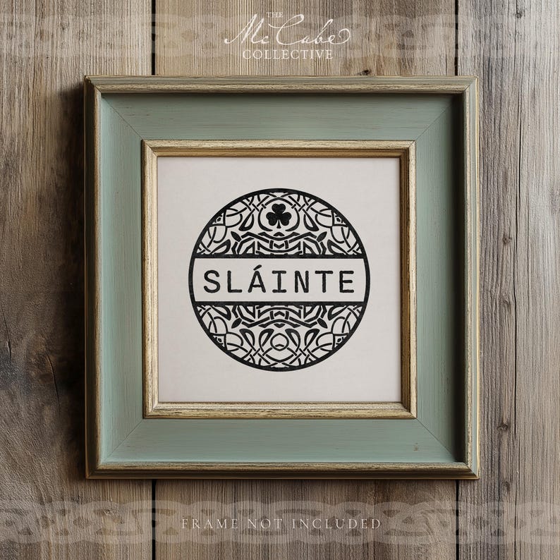 May include: A square wall art piece in a sage green and gold frame featuring a circular black and white graphic. The design includes intricate Celtic knotwork, a small shamrock icon at the top, and the word SL&Aacute;INTE printed in bold black capital letters.