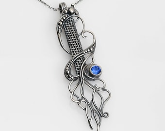 Puede incluir: Un collar de plata con un colgante que presenta una piedra preciosa azul y un intrincado diseño de alambre.