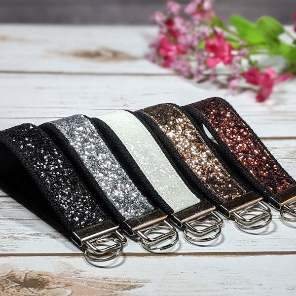 Llavero de muñeca con brillantina en lona, negro, blanco, cobre y plata.