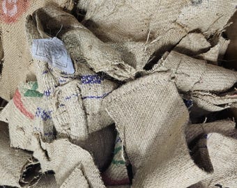 May include: A pile of brown hessian fabric scraps with some blue and green markings. The fabric is woven and has a rough texture.